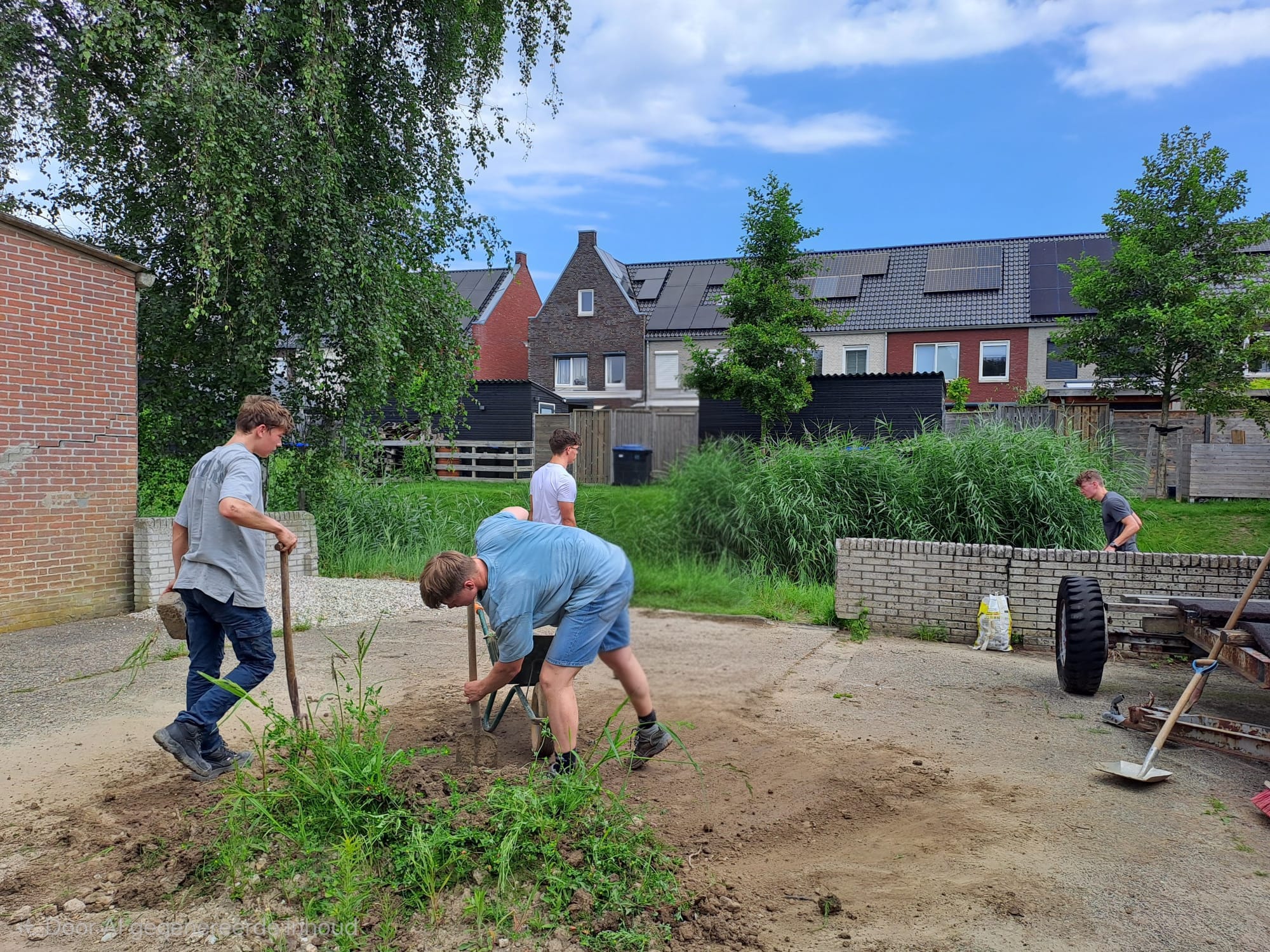 Vier jongens hogen met kruiwagens en schoppen een achterterrein langs het water op in Middelharnis.